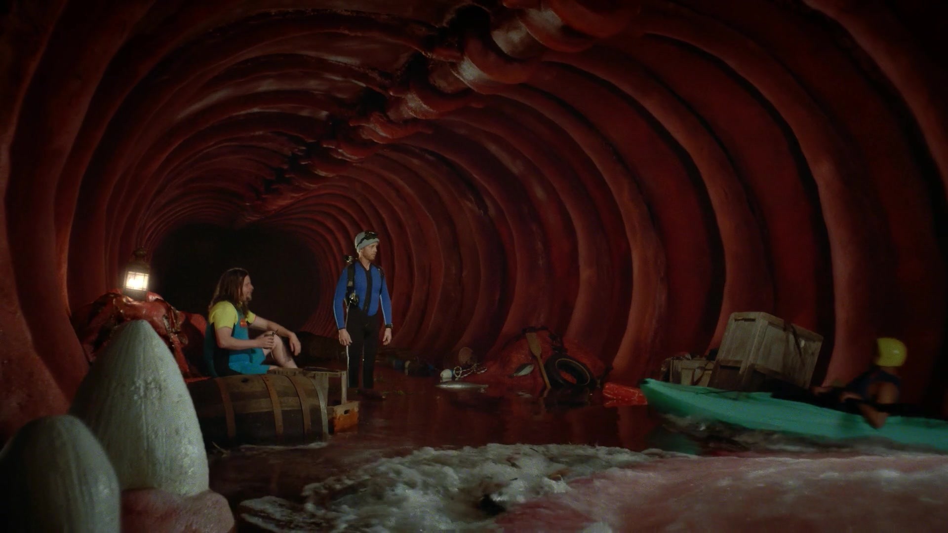 Two divers inside whale belly with shark fins in foreground and kayaker swept in from right.