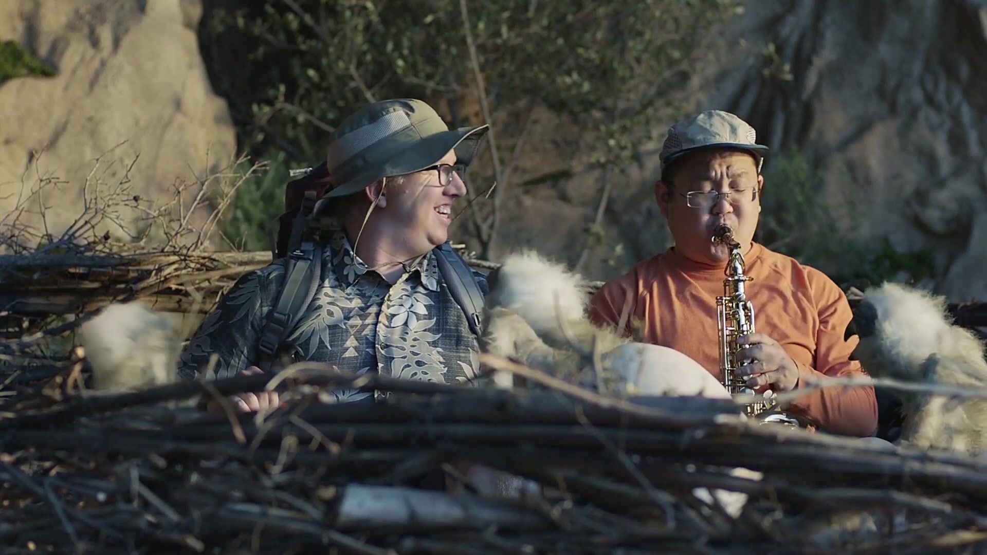 Hike — two hikers sit in a giant nest with furry hatchlings while one plays a saxophone