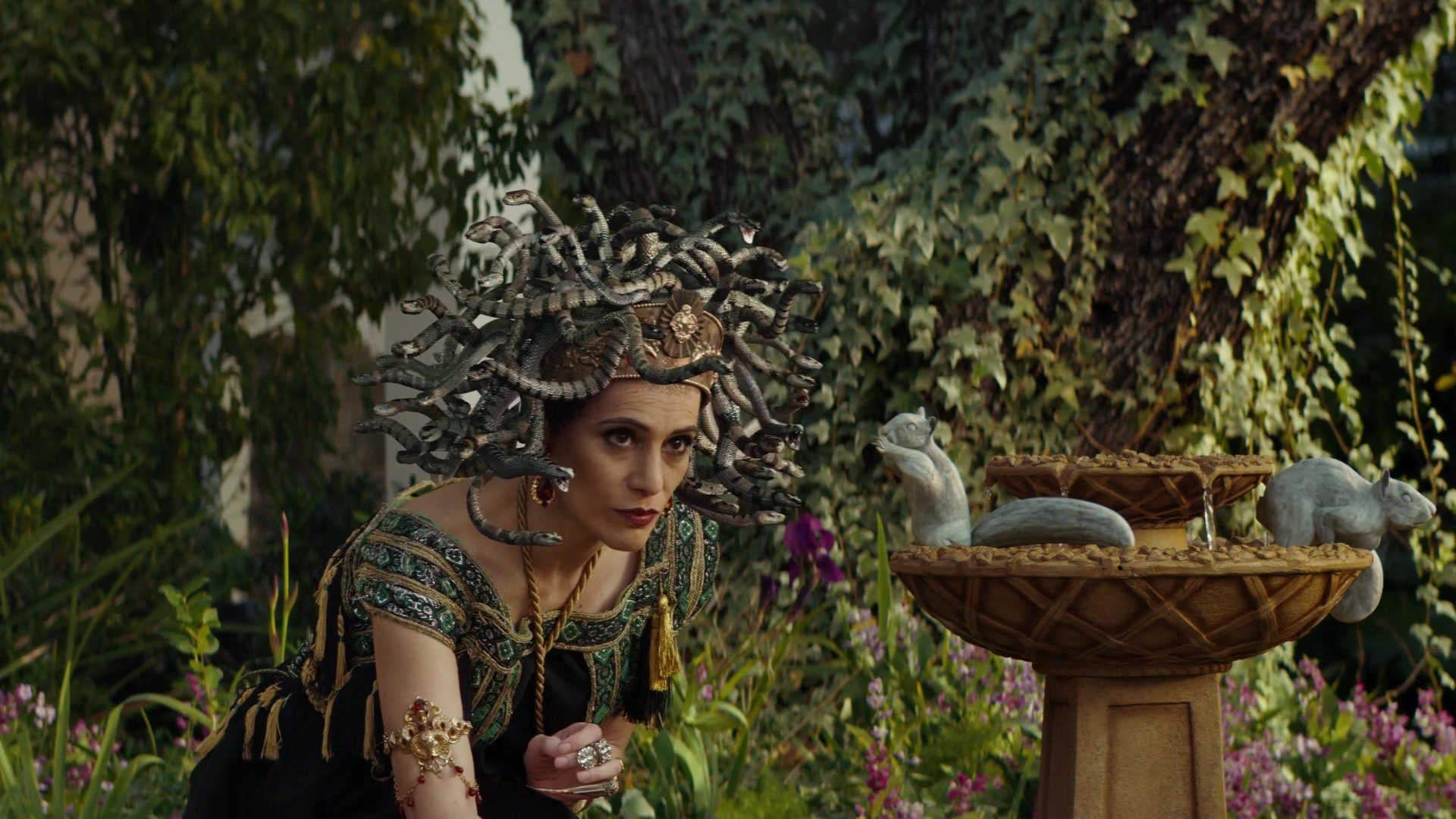 Landscaper — Medusa tends the garden beside squirrels turned to stone around a fountain