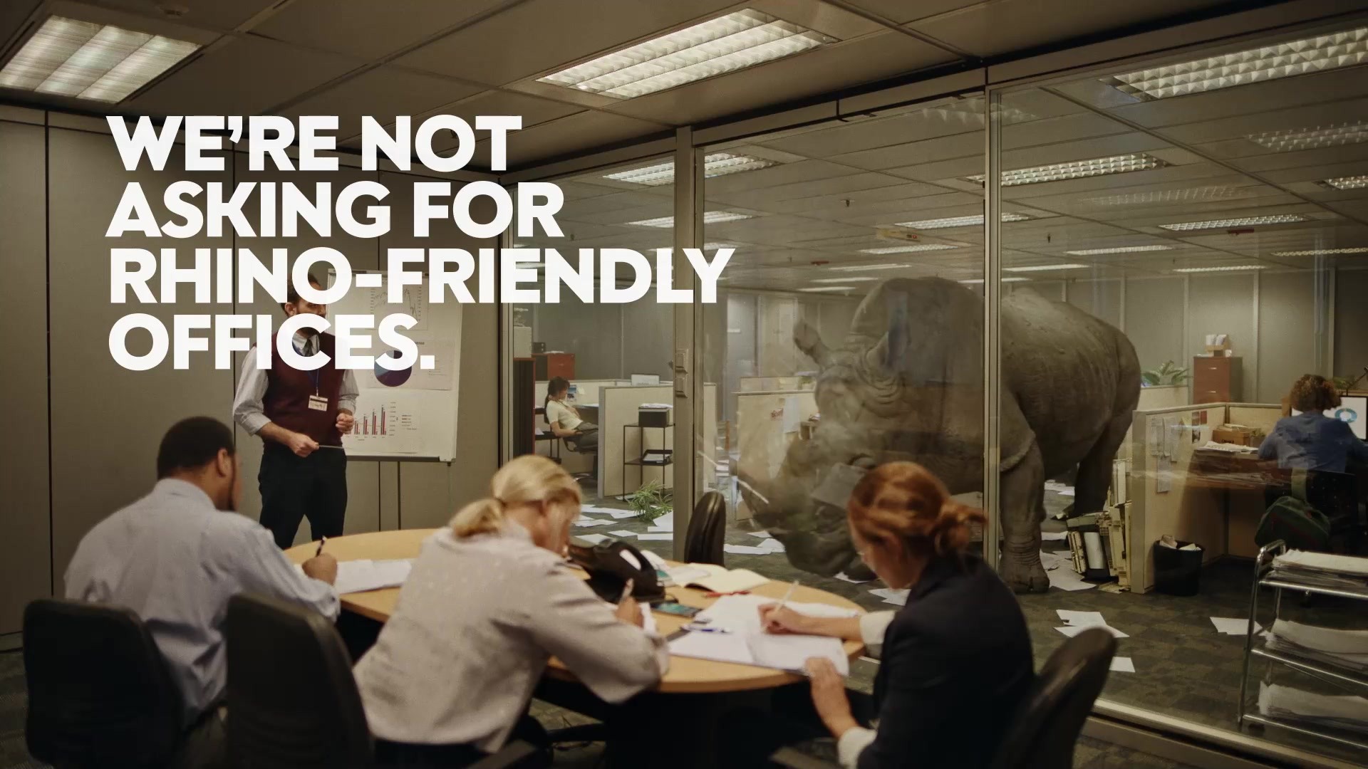 Rhino — the rhinoceros touches the intact conference-room glass just before it shatters