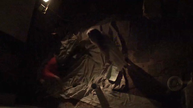 A figure bursts from the draped furniture in the dark haunted house